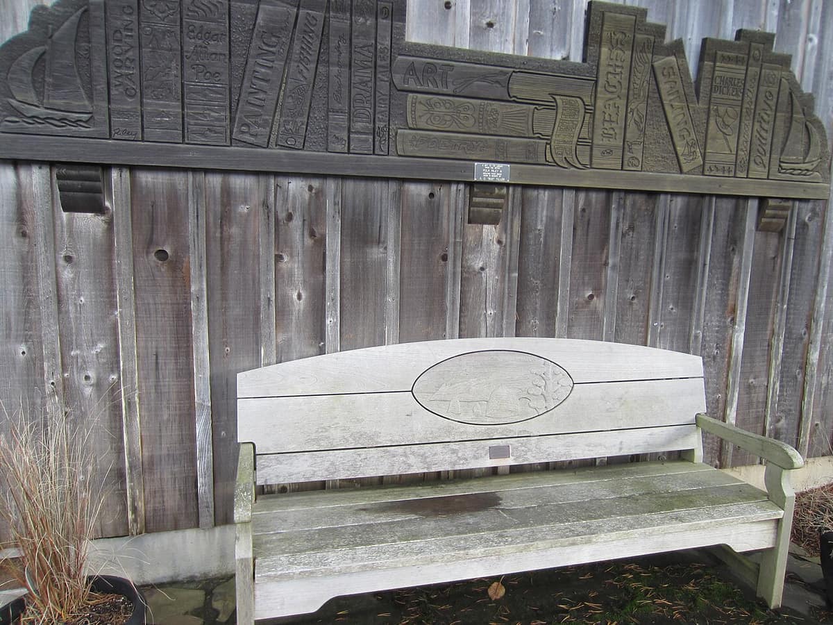 carved wooden relief of books and sailboats above a bench in Cannon Beach