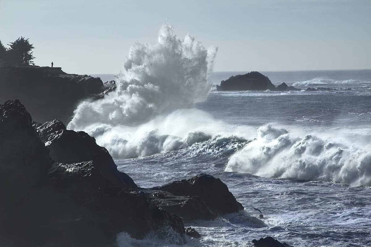 Large storm waves breaking against dark rocks on the Oregon coast near Coos Bay