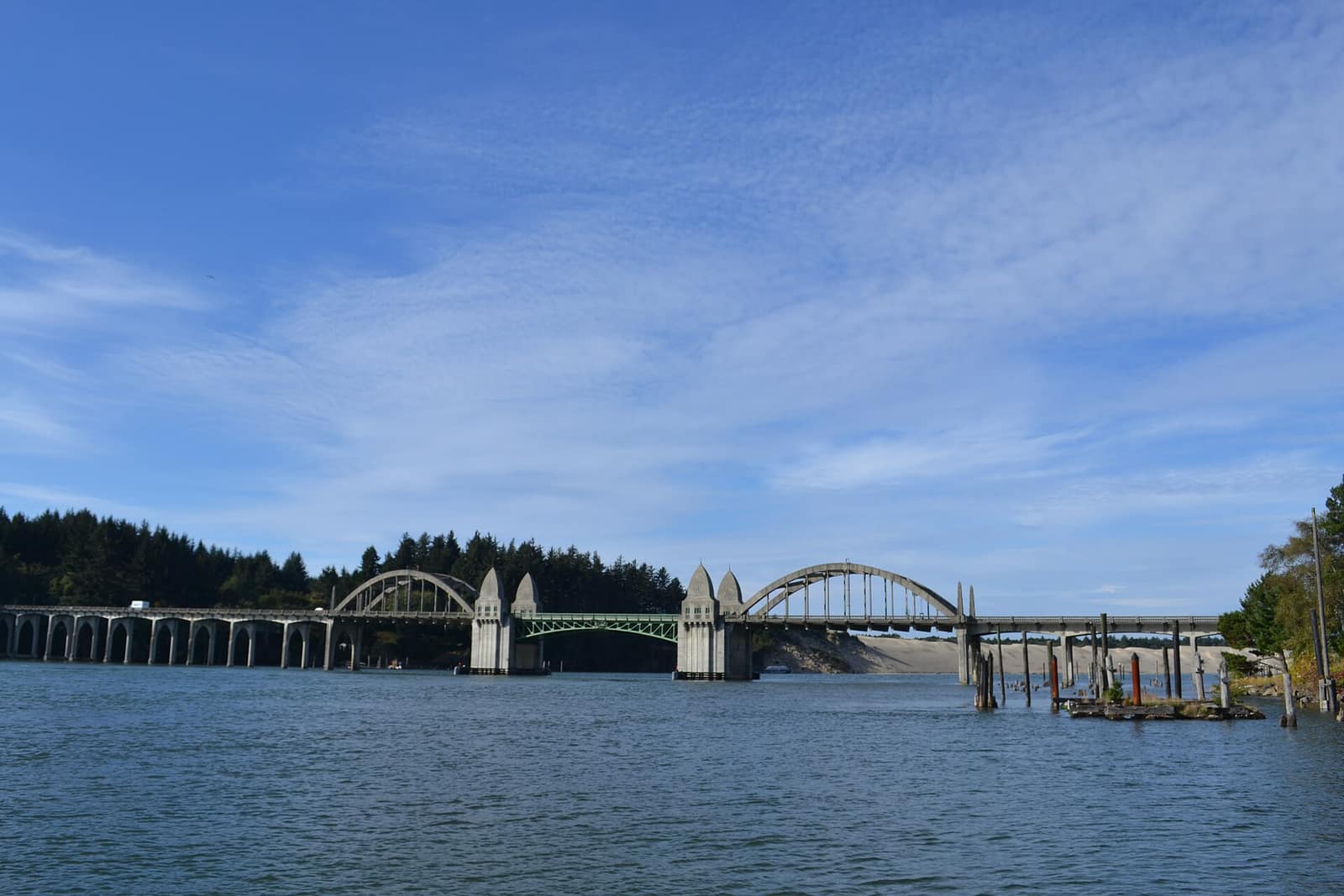 The Siuslaw River Bridge with its arches and towers crossing the river, sand dunes visible behind
