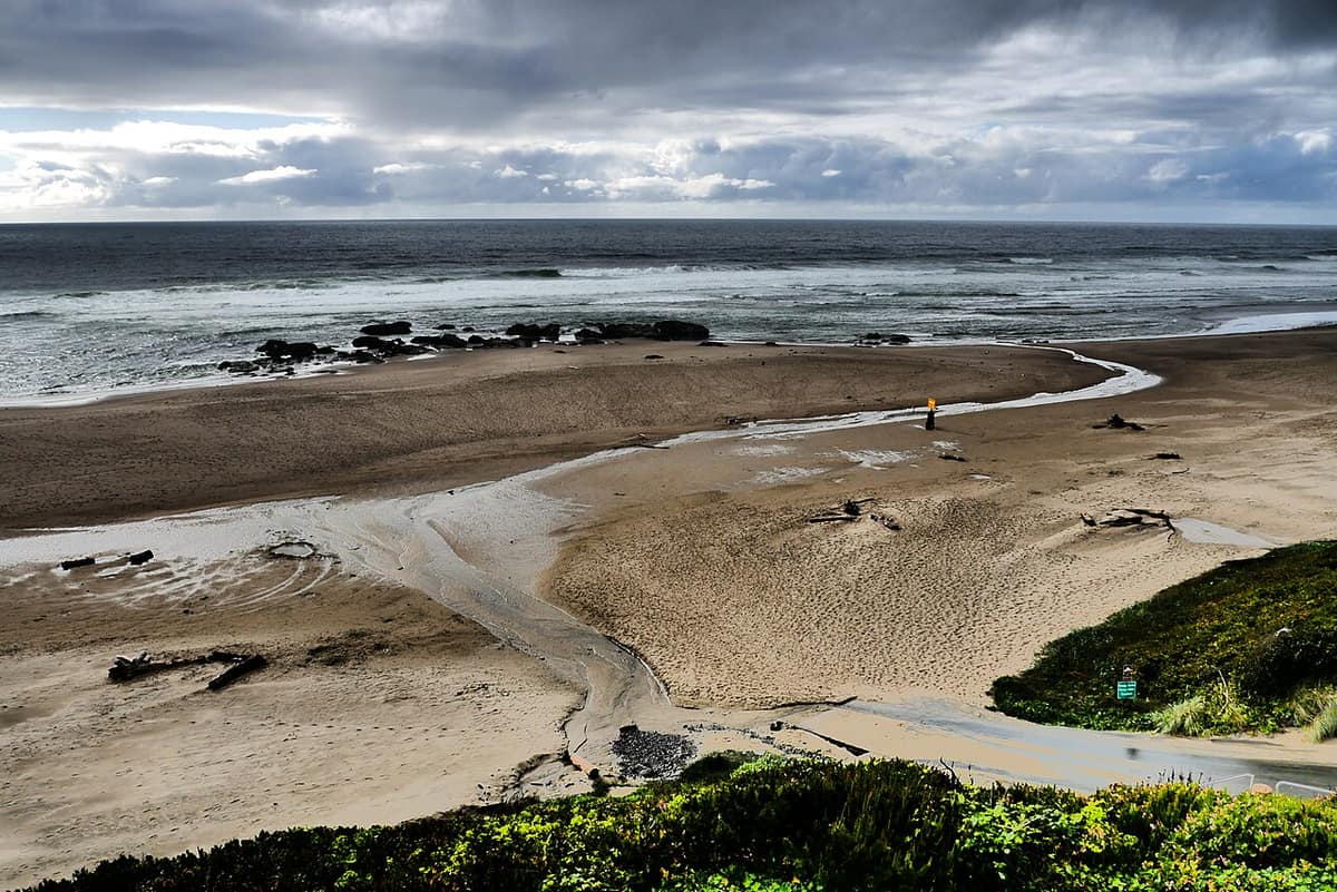 Empty sandy beach and surf in Lincoln City, Oregon under storm clouds
