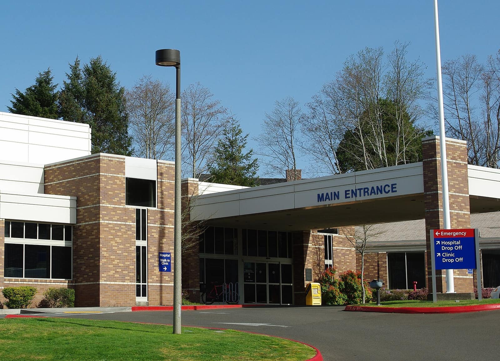 Main entrance of Providence Seaside Hospital, a brick and white building with an entrance canopy and signs pointing to the emergency department